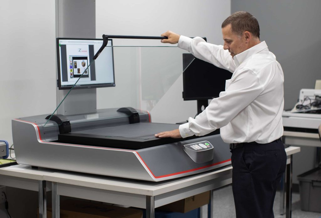 A QAI employee operating a piece of document conversion equipment