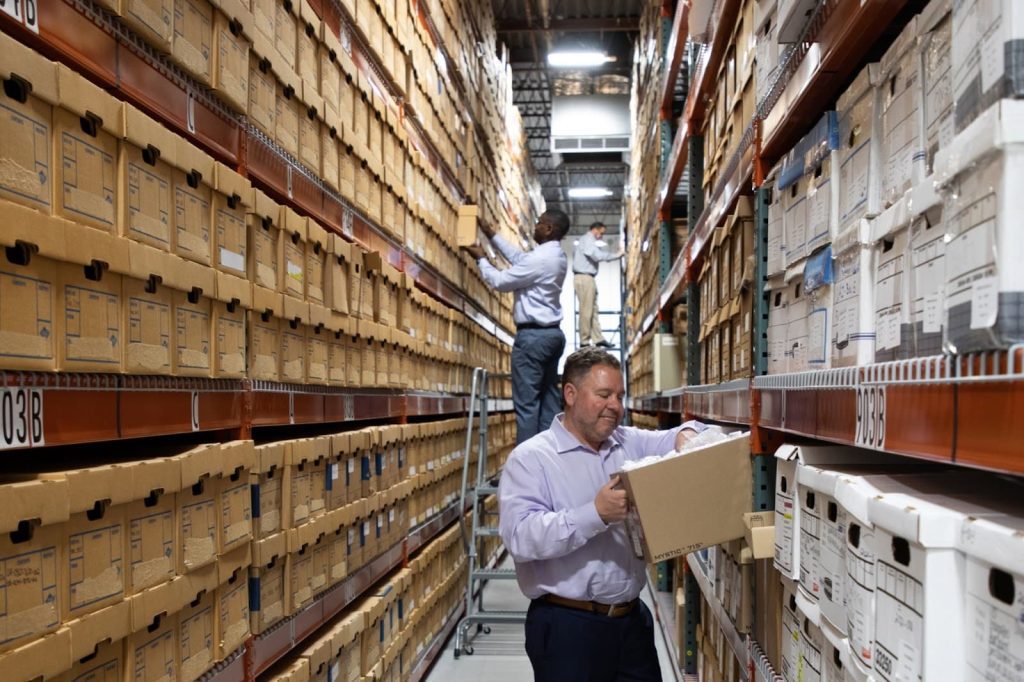 People in a storage facility looking inside boxes