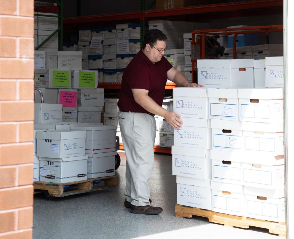 A QAI employee moving boxes in a warehouse
