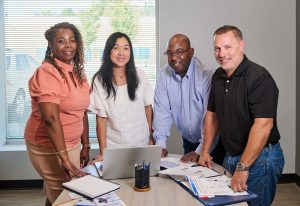 A group of QAI employees gathered around a table