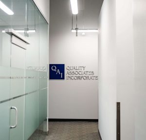 The Quality Associates, Inc. logo mounted on a wall