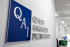 The Quality Associates, Inc logo on a wall